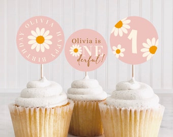 May include: Three pink and white cupcake toppers with a daisy design. The toppers say "Olivia is one derful!" and "Happy Birthday Olivia". One topper has the number "1" on it.