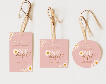 May include: Three pink thank you tags with white daisy flowers and brown string. The text on the tags reads "Thank you for making my birthday one derful! Love, Olivia."