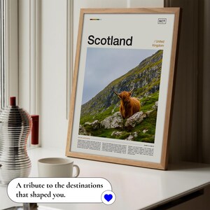 May include: Framed print featuring the word "Scotland" and an image of a Highland cow on a hillside. The print has a light wood frame and includes the text "United Kingdom" and "SCT". The bottom of the image has the text "A tribute to the destinations that shaped you."