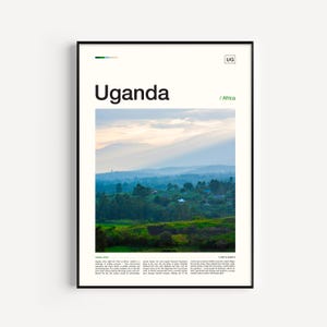 May include: A framed poster with the word "Uganda" in large black text, with "/ Africa" below it. The image is a landscape of green hills and trees under a cloudy sky. The poster has a black frame.