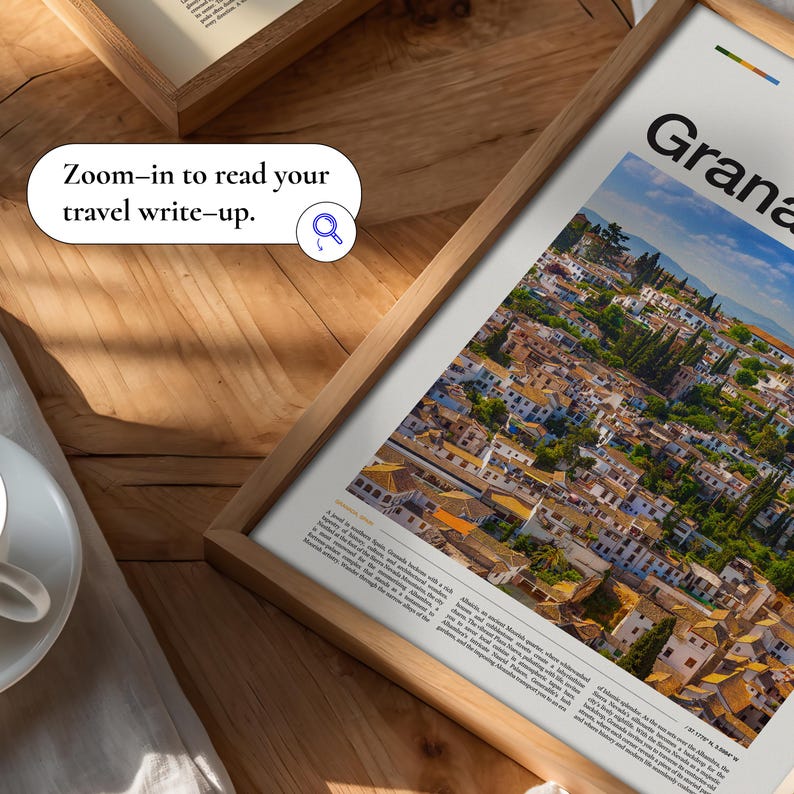 May include: A framed print featuring a vibrant aerial view of Granada, Spain, with white buildings and terracotta rooftops under a blue sky. The print is in a light wood frame. Text on the print reads "Granada" and "Zoom-in to read your travel write-up."
