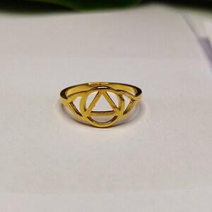 Op de afbeelding: Gouden ring met een cirkel- en driehoeksontwerp. De ring is een symbool van de derde oogchakra.