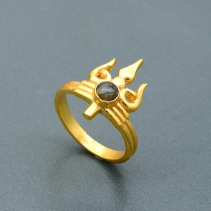 Puede incluir: Anillo de oro con un diseño de tridente con una piedra preciosa negra.