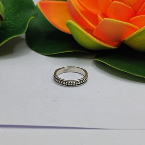 May include: A silver ring with a beaded design around the band.