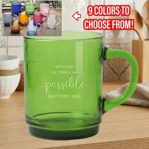 May include: A green glass mug with a matching handle. The mug has the words "With God All Things Are Possible Matthew 19:26" in white script. The image also shows a variety of other colored mugs.