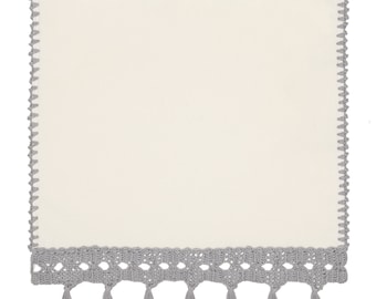 May include: A white crocheted hand towel with gray crochet trim and tassels. The towel is hanging on a silver towel bar.