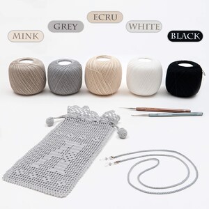 May include: Five balls of yarn in different colors: mink, grey, ecru, white, and black. The yarn is arranged in a row on a white surface. There is a crocheted bag, a crochet hook, and a grey cord on the surface.
