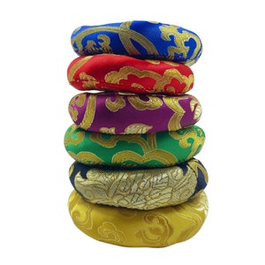 May include: A stack of six colourful meditation cushions with gold embroidery. The cushions are made of fabric and are round in shape.