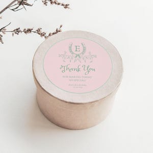 Puede incluir: Una caja de regalo de agradecimiento rosa y gris con una herradura y la letra E en el centro. El texto en la caja dice "Gracias por hacer que este día sea tan especial".