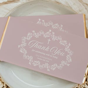 May include: Pink thank you card with a white floral design and the text "Thank You for celebrating with us today Lucy's Baptism! October 24th, 2023".