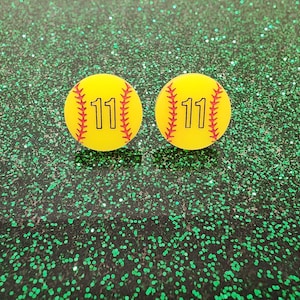 May include: Two yellow softball earrings with red stitching and the number 11 printed in black.