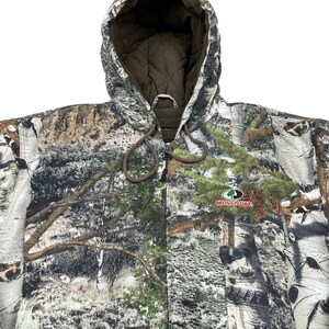 May include: A hooded camouflage jacket with a drawstring closure. The jacket features a forest pattern with shades of green, brown, and white. The Mossy Oak logo is visible on the front. The interior lining is a solid brown color.