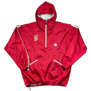 May include: A red hooded anorak jacket with a white zipper and white accents. The jacket features the "Amstel Light" logo on the chest and a small logo on the right side. The jacket has a drawstring at the bottom.