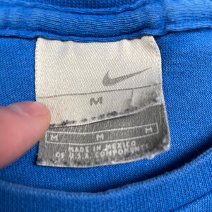 Puede incluir: Una taza de cer&aacute;mica blanca con un asa negra y el texto "But First, Coffee" en negro, en negrita. La taza est&aacute; sobre una superficie blanca.