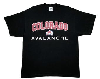 May include: Black t-shirt featuring the word "COLORADO" in a red and white arched design, with the word "AVALANCHE" below in white. The shirt also has a logo of a mountain with a red and white design.