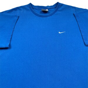 Puede incluir: Una taza de cer&aacute;mica blanca con asa negra y el texto "But First, Coffee" en negrita negra. La taza est&aacute; llena de un l&iacute;quido oscuro, probablemente caf&eacute;, y se encuentra sobre una superficie clara.