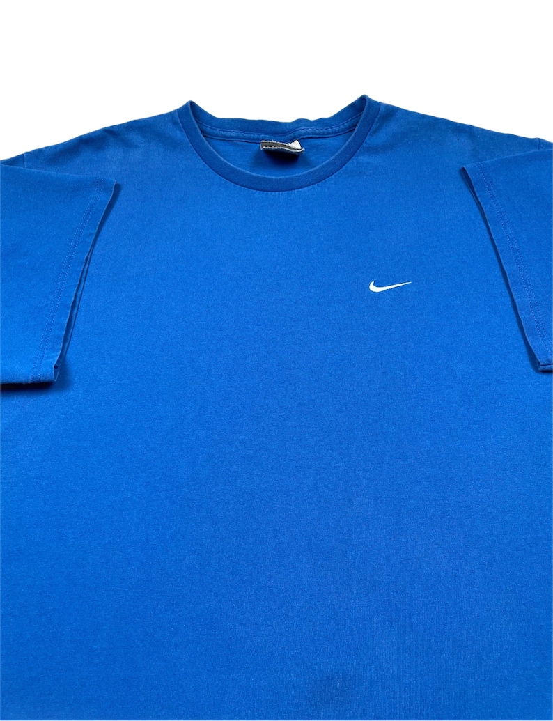 Puede incluir: Una taza de cer&aacute;mica blanca con asa negra y el texto "But First, Coffee" en negrita negra. La taza est&aacute; llena de un l&iacute;quido oscuro, probablemente caf&eacute;, y se encuentra sobre una superficie clara.