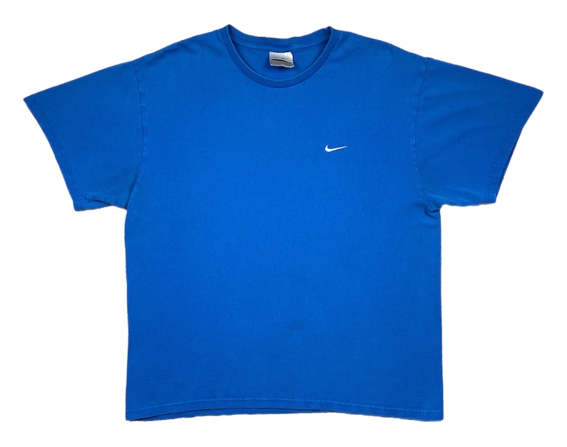 Puede incluir: Una camiseta azul liso con cuello redondo y mangas cortas. Un peque&ntilde;o logotipo blanco de Nike est&aacute; bordado en el pecho izquierdo. La camiseta est&aacute; hecha de un material suave, probablemente algod&oacute;n.