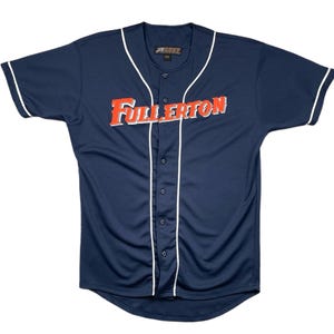 Könnte beinhalten: Marineblaues Baseball-Trikot mit weißer Paspelierung und dem Wort "Fullerton" in Orange und Weiß auf der Brust. Das Trikot hat eine Knopfleiste und kurze Ärmel. Größe XXL.