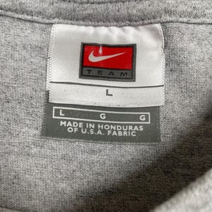 Op de afbeelding: Een witte keramische mok met een zwart handvat en de tekst "But First, Coffee" in een zwarte, handgeschreven lettertype. De mok staat op een wit oppervlak.