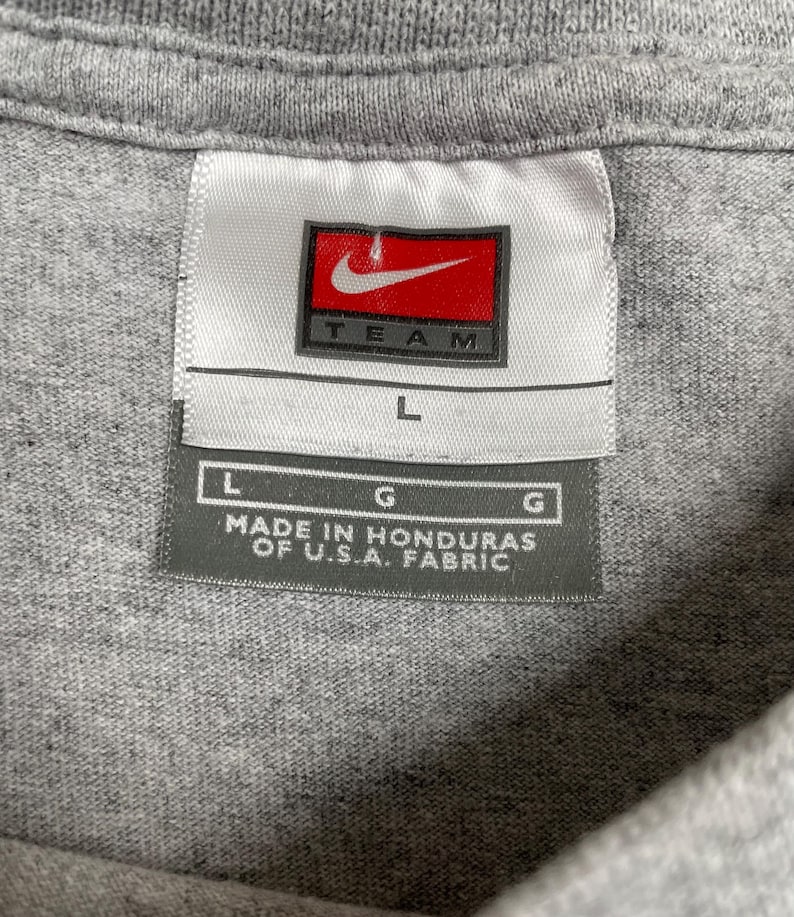 Op de afbeelding: Een witte keramische mok met een zwart handvat en de tekst "But First, Coffee" in een zwarte, handgeschreven lettertype. De mok staat op een wit oppervlak.