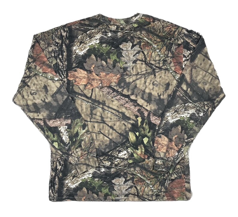 May include: Long-sleeved camouflage shirt in shades of brown, green, and tan. The shirt features a crew neck and a pattern designed to blend with natural environments. The fabric appears to be a lightweight material, suitable for outdoor activities.