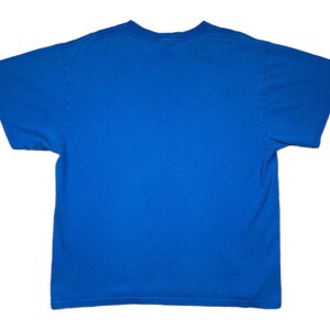 Puede incluir: Una camiseta azul lisa con mangas cortas y cuello redondo. La camiseta es de un tono azul brillante y parece estar hecha de una tela suave, posiblemente algod&oacute;n o una mezcla de algod&oacute;n. Una prenda sencilla para el d&iacute;a a d&iacute;a.