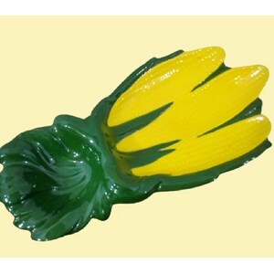May include: A green and yellow ceramic corn cob dish. The dish is shaped like a corn cob with green husks and yellow kernels.