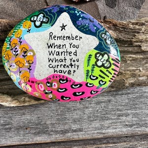 May include: A painted rock with a colorful design and the text "Remember when you wanted what you currently have?"