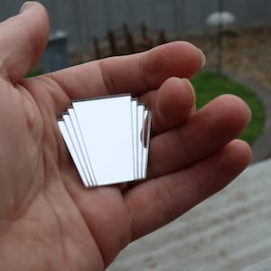 May include: A silver mirrored art deco design with a geometric shape.