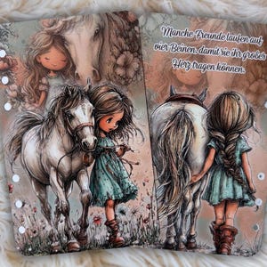 Pu&ograve; includere: Due pagine illustrate con una ragazza e un cavallo. La ragazza indossa un vestito verde acqua e stivali marroni. Il cavallo &egrave; bianco con una briglia marrone. Il testo in tedesco recita: "Alcuni amici camminano su quattro zampe per poter portare il loro grande cuore."