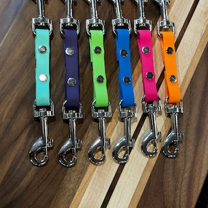 May include: Six colorful dog leash attachments with silver swivel clips. The leashes are made of a durable, rubber-like material and come in the colors teal, purple, green, blue, pink, and orange.