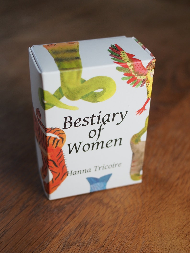 May include: A white box with colorful illustrations of animals, including a snake, a bird, and a tiger. The box is titled "Bestiary of Women" with the author's name, Hanna Tricoire, printed below.