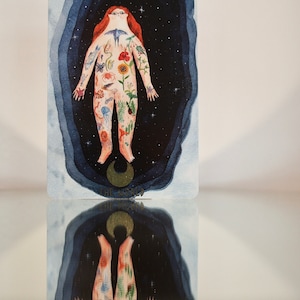 Puede incluir: La carta del tarot El Mundo presenta una ilustraci&oacute;n de acuarela de una persona cuyo cuerpo est&aacute; cubierto de im&aacute;genes inspiradas en la naturaleza, incluyendo flores, animales y cuerpos celestes. La persona est&aacute; rodeada de un fondo azul oscuro con estrellas y una luna creciente.