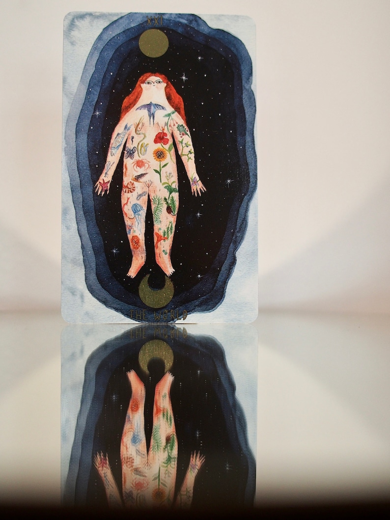 Puede incluir: La carta del tarot El Mundo presenta una ilustraci&oacute;n de acuarela de una persona cuyo cuerpo est&aacute; cubierto de im&aacute;genes inspiradas en la naturaleza, incluyendo flores, animales y cuerpos celestes. La persona est&aacute; rodeada de un fondo azul oscuro con estrellas y una luna creciente.