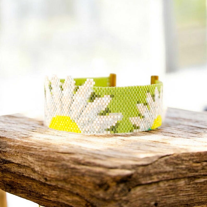 Pu&ograve; includere: Un braccialetto di perline verdi e bianche con un design a margherita. Il braccialetto &egrave; realizzato con piccole perline a seme e presenta un centro giallo sulla margherita.