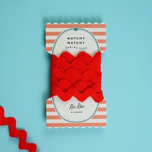 Op de afbeelding: Felrood ric rac lint met een golvende, geschulpte rand op een kaart. De kaart heeft de tekst "Matchy Matchy Sewing Club" en "Ric Rac 3 yards". De kaart heeft een gestreept ontwerp en een geschulpte rand.
