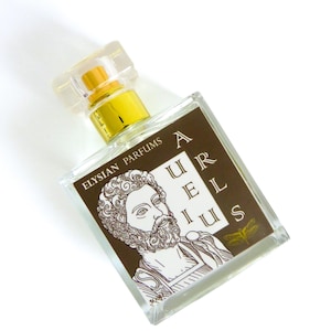 May include: A clear glass bottle of perfume with a gold cap. The bottle has a brown label with the text "ELYSIAN PARFUMS" and "AURELIUS" in a stylized font. A drawing of a man with a beard is on the label. A gold dragonfly is on the label.