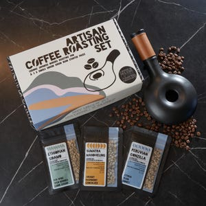 May include: A coffee roasting set featuring a ceramic Japanese HoroKu roasting pan, three single origin green bean starter packs, and a black ceramic roasting funnel. The set is packaged in a box with a colourful abstract design and the text "Coffee Artisan Roasting Set".