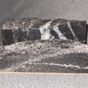 May include: Two stacked black and white marble blocks with a rough, textured surface.