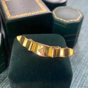 May include: A gold-toned brooch with a single diamond in the centre, set in a green velvet box.