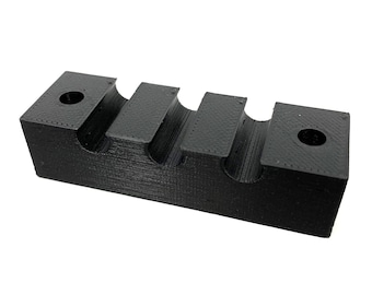 May include: Black plastic organizer with four slots for holding items. The organizer has a textured surface and two small holes on the top.