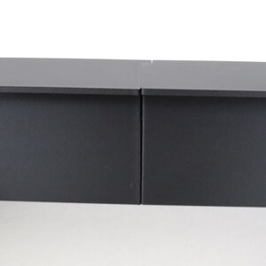 May include: Two black rectangular shelves, side by side, with a slight gap between them.