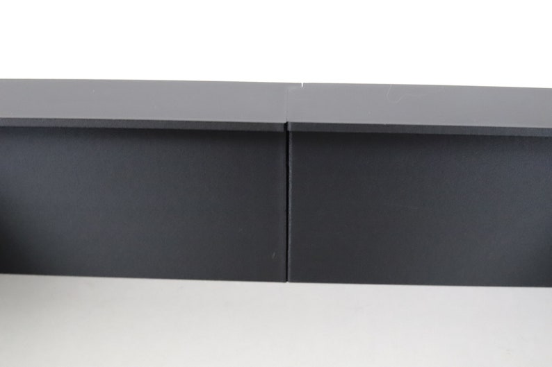 May include: Two black rectangular shelves, side by side, with a slight gap between them.