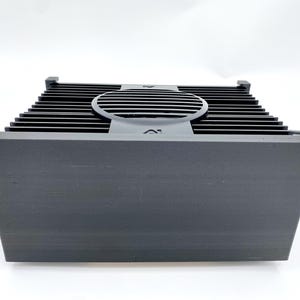 Könnte beinhalten: Schwarzer rechteckiger Audioverstärker mit einem großen Metallkühlkörper und einem runden Lüfter oben.