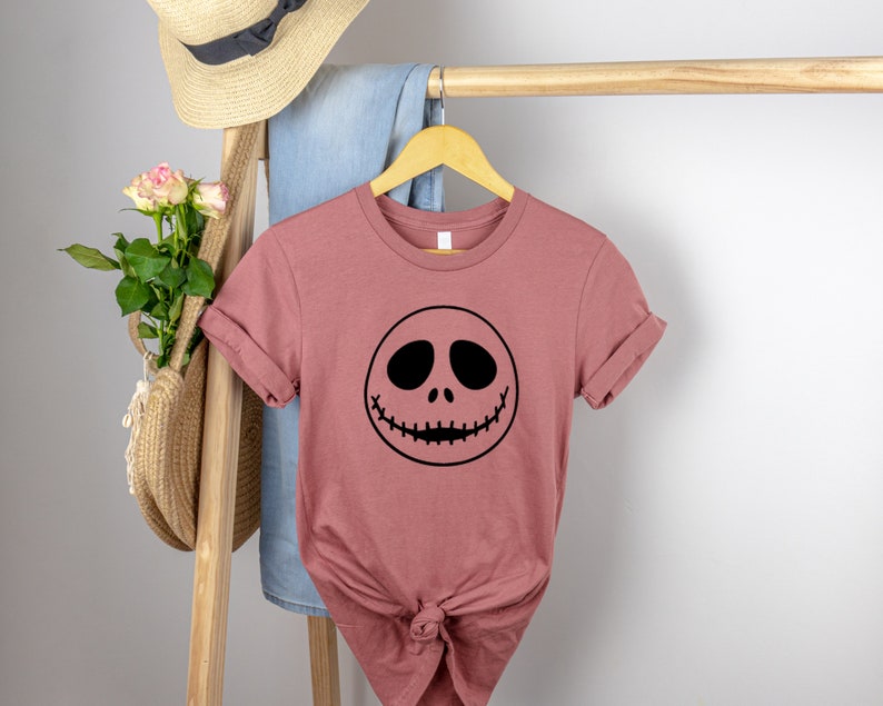 May include: A mauve t-shirt with a black Jack Skellington face graphic.