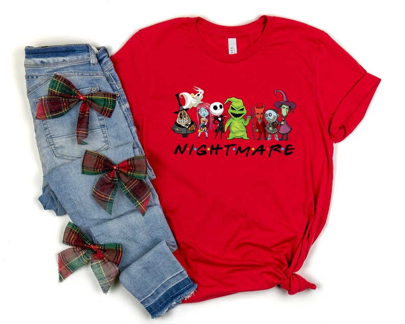 May include: Red t-shirt featuring a graphic of characters from the Nightmare Before Christmas film. The characters are arranged in a line with the text "NIGHTMARE" underneath. The shirt is styled with blue jeans and red and green plaid bows.