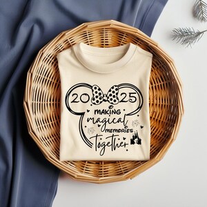以下が含まれることがあります： クリーム色のTシャツに、黒いミッキーマウスの耳のデザインと「2025 Making Magical Memories Together」の文字が書かれています。