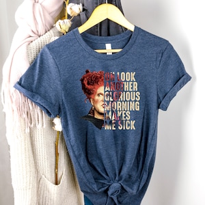 May include: A navy blue t-shirt with a graphic of a woman with red hair and the text "Oh look another glorious morning makes me sick".