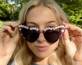 May include: Black cat-eye sunglasses with rhinestones and the words "HELL YEAH DAMN RIGHT" spelled out in white letters.